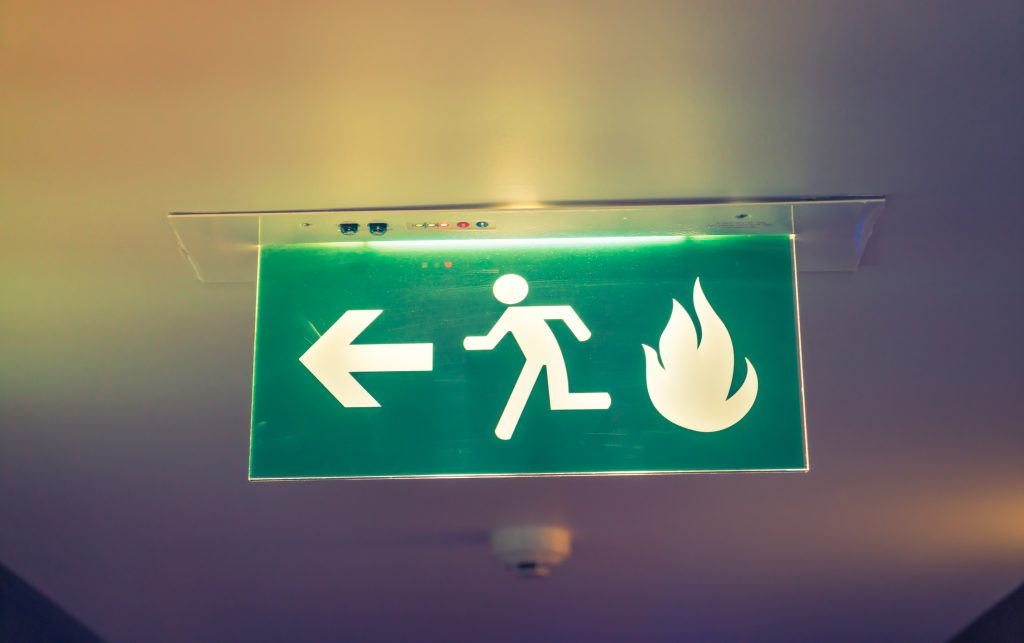Fire escape signage directing occupants to a safe exit as part of a building’s fire door inspection and fire safety strategy.