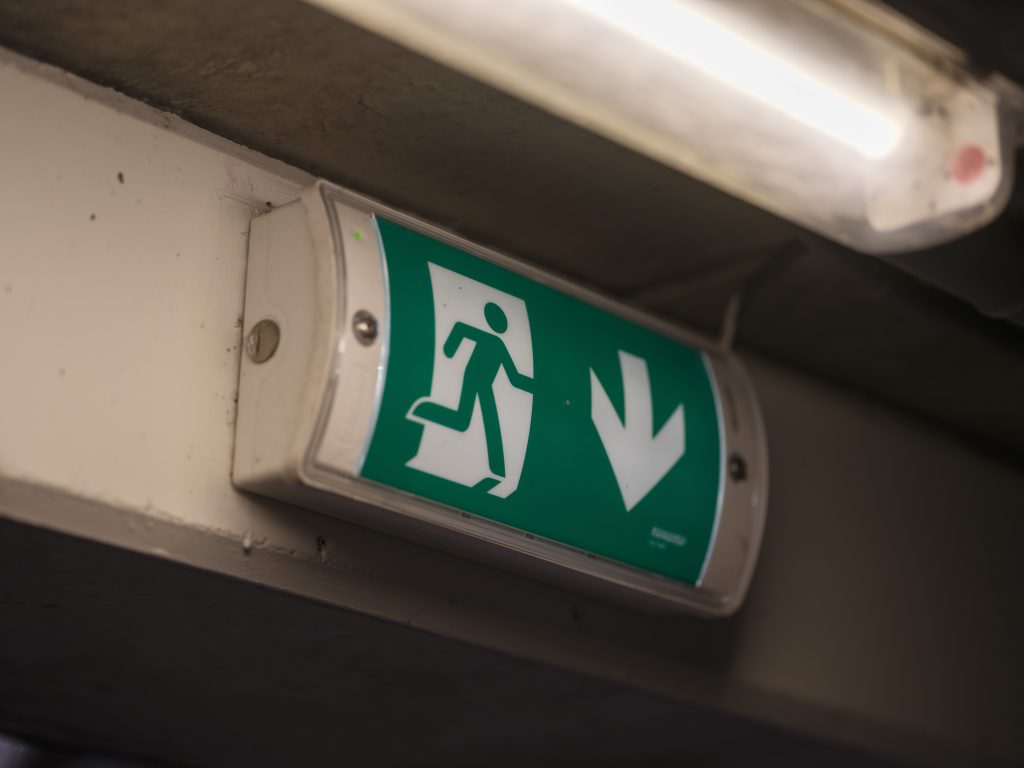 Emergency exit sign installed above a fire door, highlighting a key feature checked during a fire door inspection for building fire safety compliance.