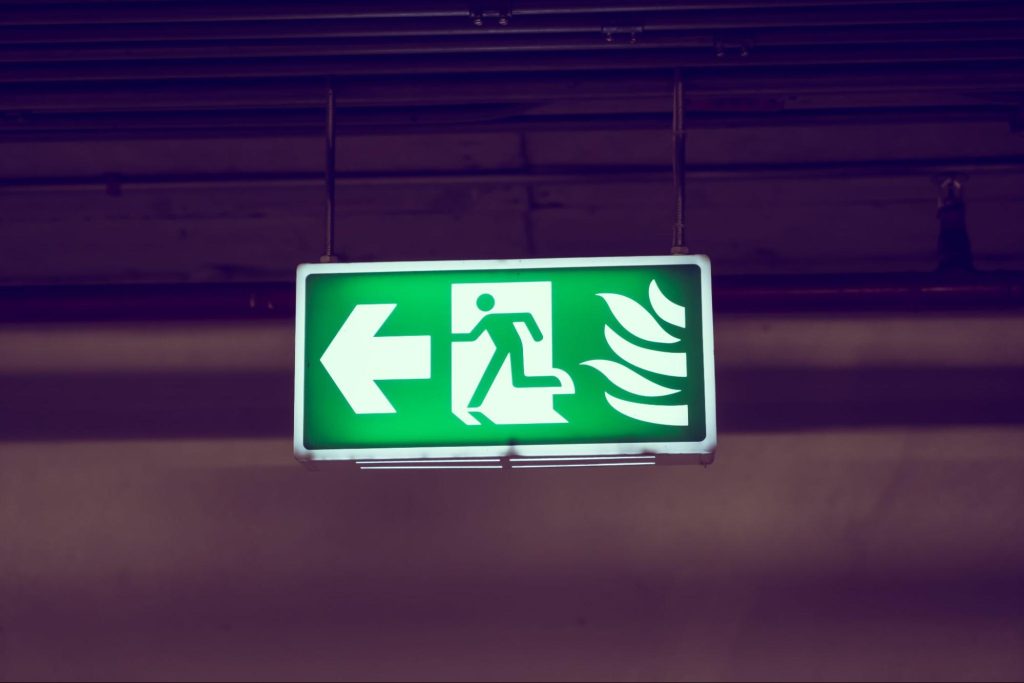 Emergency lighting illuminated exit sign marking the designated escape route inside a residential building.