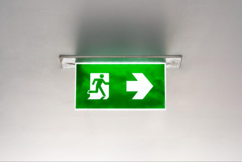Illuminated emergency exit sign installed as part of an emergency lighting system, supporting compliance with emergency lighting regulations and safe evacuation routes.